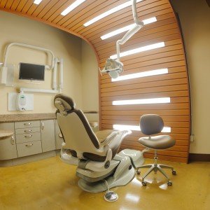 Curved timber slatted ceiling running down the wall of a dental surgery above the chair.