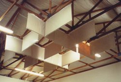 White baffles hung in a staggered grid from the steel roof structure of a large room.