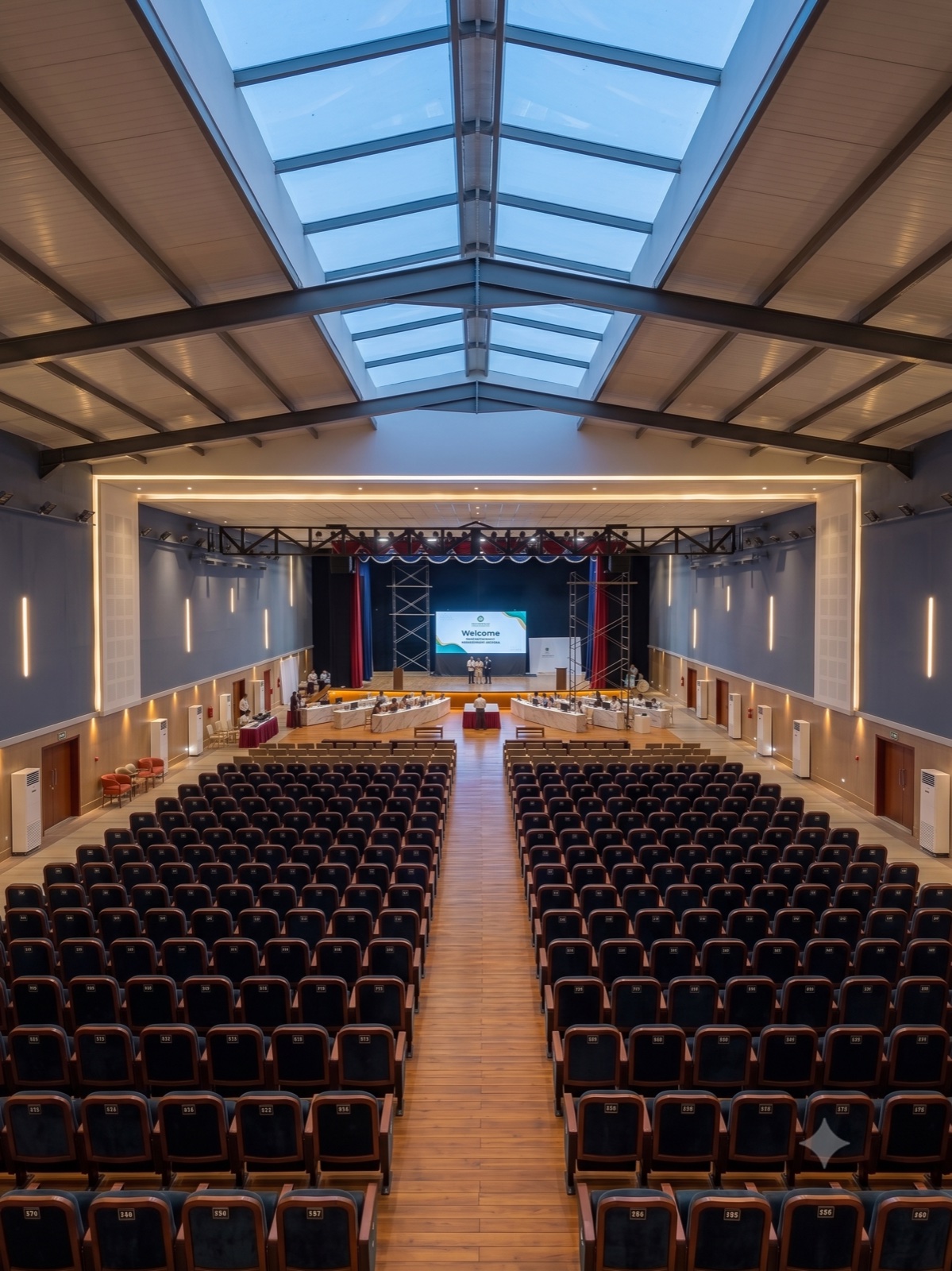 An auditorium seen from the rear, stage lit at the far end and seating running to it.